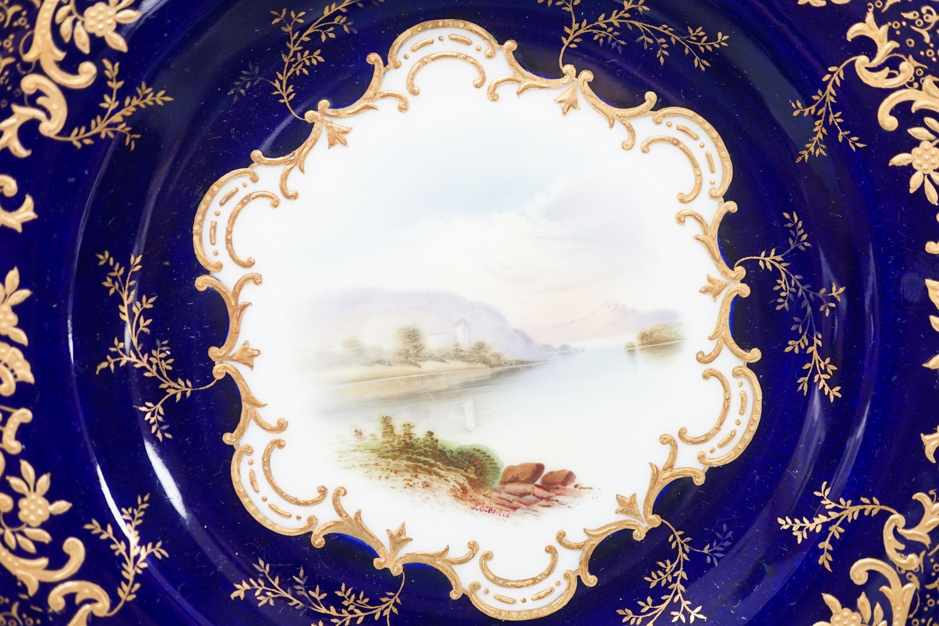 A pair of Coalport landscape plates painted by J. Oldfield with loch scenes, impressed date code for 1909, diameter 23cm